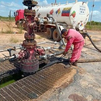 Technician working at a wellhead next to a tanker truck