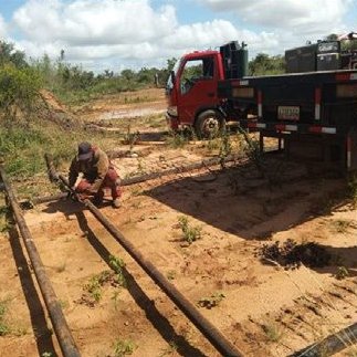 Crew laying crude oil pipes beside a mobile welding truck
