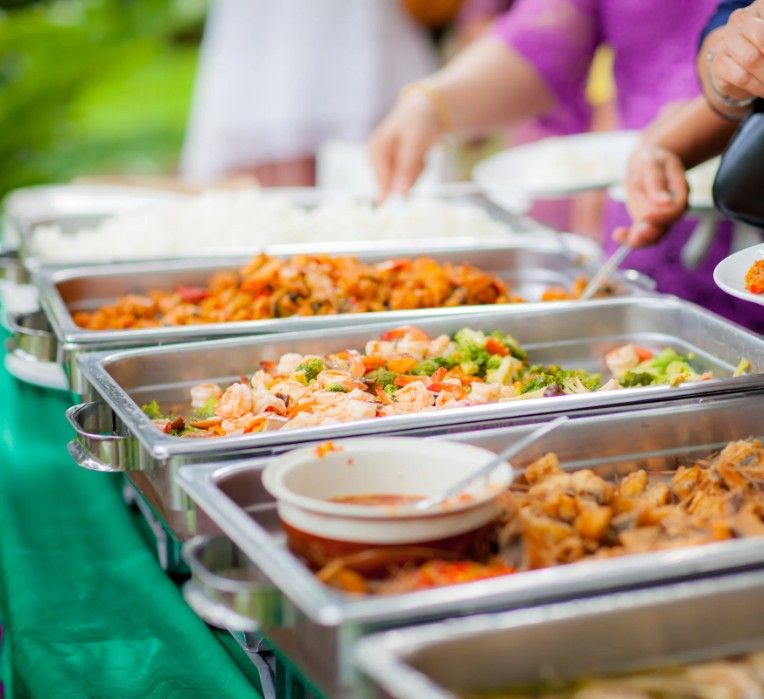 Hot dishes in chafing trays on a catering serving line.