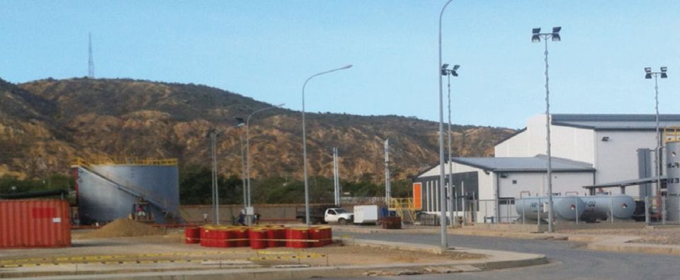 Cumaná plant: industrial buildings, tanks and light poles in the industrial zone, with hills in the background.