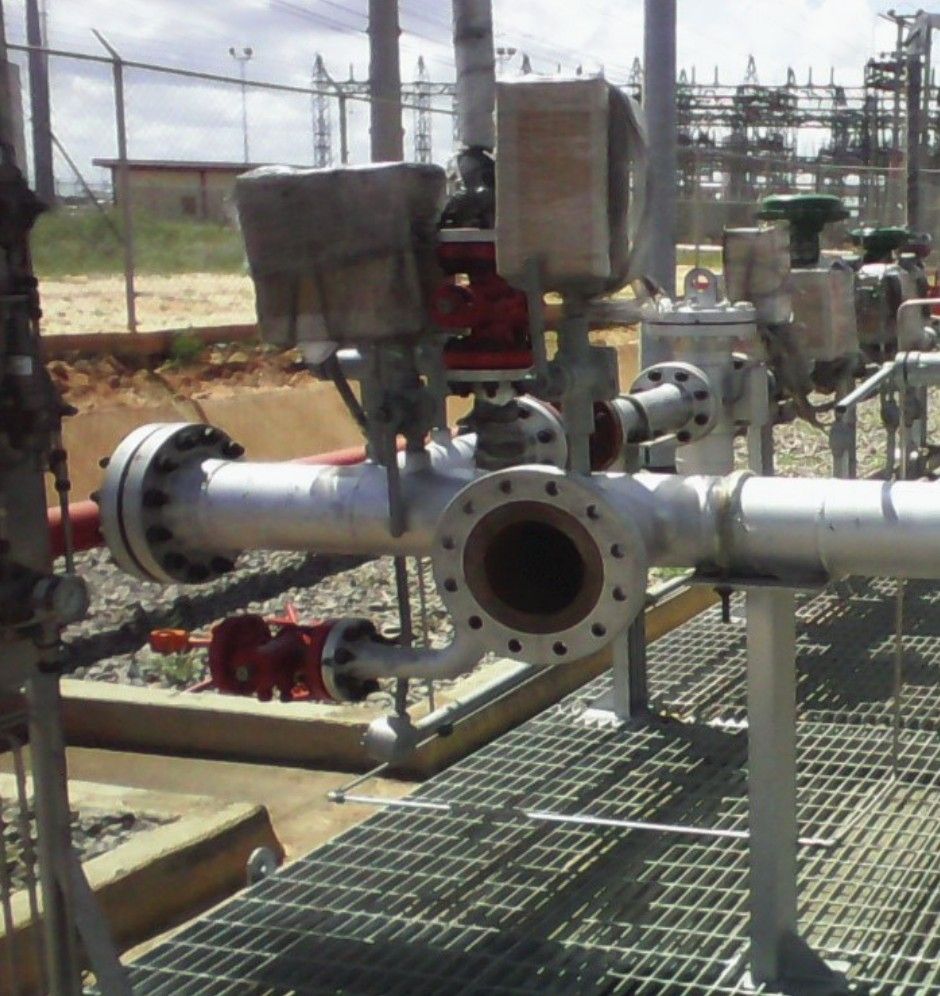 Regulation and metering station: flanged piping, valves and filters on a grating floor.