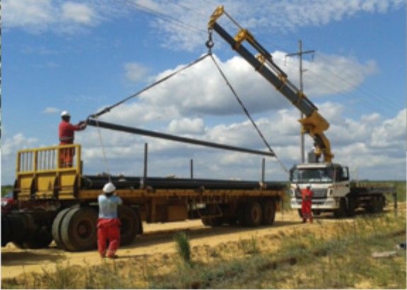 Unloading pipe from a flatbed truck with an articulated crane.