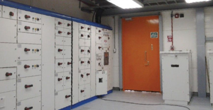 Electrical room with distribution switchgear and an orange access door.